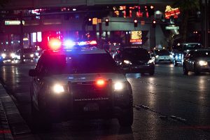 A photo of a police car on a city street at night with its lights on.